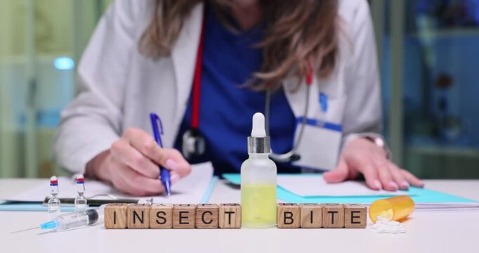 Wooden blocks on desk spell words Insect Bite beside dropper bottle. Doctor tests skin reaction drops noting emergency treatment plan at appointment