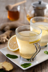 Ginger tea with honey and lemon in a cup on wooden table