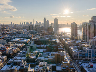 Aerial view of a city's rooftops dusted with snow leading to a skyline punctuated by towering buildings and the shimmering water, Brooklyn, New York, United States.