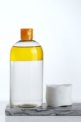Minimalist scene featuring a two-phase makeup remover with oil and cotton pads