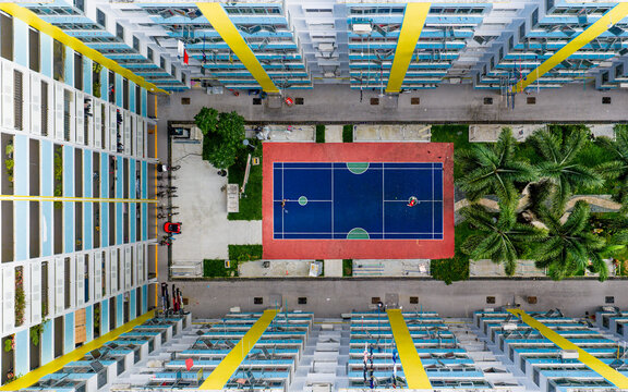 Aerial view of the blue and red badminton sports court nestled between towering HDB flats, a splash of vibrant color amid the urban landscape, Singapore, Singapore.