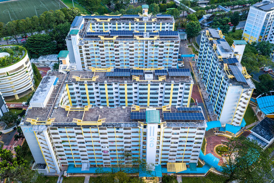 Aerial view of HDB flats with solar panels glinting under the sun, casting long shadows over the urban landscape, Singapore, Singapore.