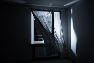 The wind from the window flutters the curtains in the old house in the moonlight.