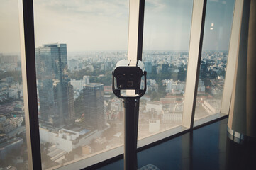 Indoor observation deck with panoramic viewer overlooking the city skyline