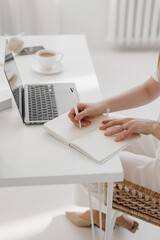 Person Writing in Notebook with Laptop and Coffee