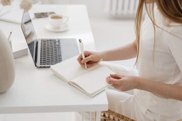 Person Writing in a Notebook at a Desk