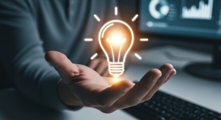 Hand holding glowing lightbulb icon above dark office equipment