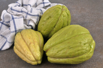 Chayotes entières et crues en gros plan isolées sur fond gris avec un torchon