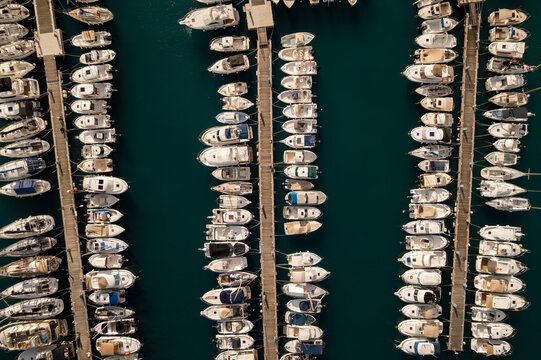 Aerial view of a harbor filled with rows of white boats gently bobbing on the dark teal water, Menton, Provence-Alpes-Cote d'Azur, France.
