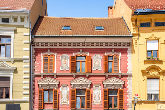Red ornate facade with windows, tympanums and artworks in the main square (Glavni Trg) of Maribor, Slovenia