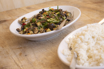healthy vegetarian stir fry with rice on wooden table