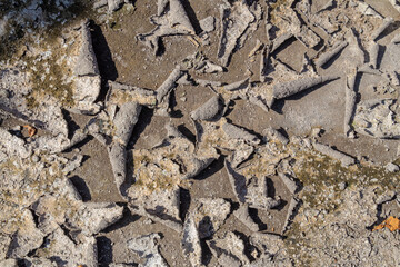 Texture of dry cracked earth ground with peeling gray mud layer and rough surface detail.