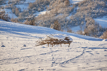 A snow-covered winter field. In the center, you can see a pile of plant supports. The tranquility of a winter day, nature is resting.