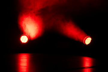 Bright red lights pierce through swirling smoke in a dimly lit space, creating an intense...