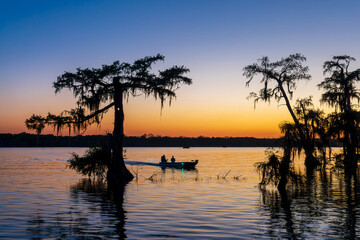 Fishing boat at Lake Martin at sunset, Cypress Island Preserve, Cypress swamp scenic landscape with reflections, Breaux Bridge near Lafayette, Louisiana