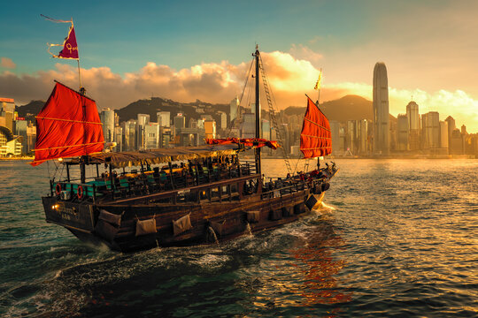 Awesome sunset view of a brightly illuminated junk boat in Victoria Harbour in front of Hong Kong's fantastic skyline with its impressive skyscrapers