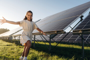 Running, having fun. Happy girl is near renewable energy equipment under bright sunlight