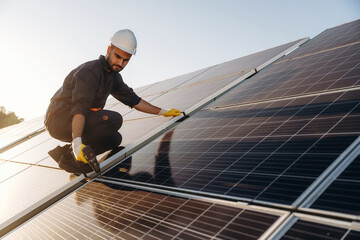 Drilling, installation process. Male solar engineer examining photovoltaic panels at a power station