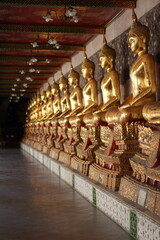 Fototapeta premium Portrait Buddha Statues in Corridor of Wat Suthat, Bangkok Thailand - One of Famous Ancient Temple in Bangkok