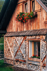 Rustic Slovenian alpine house with flower-adorned windows in scenic Bohinj valley.