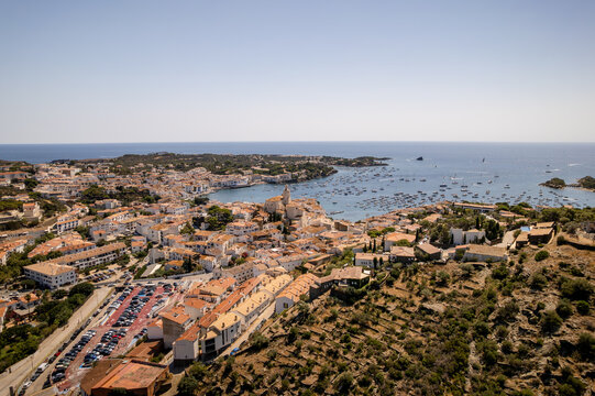 Aerial view of the white-washed buildings cascading towards the azure sea, where boats bob gently in the bay, a picturesque scene of coastal charm, Cadaques, Catalonia, Spain.