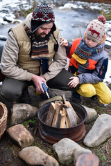 Father and son lighting a fire with a gas gun in the backyard, dressed in winter clothes