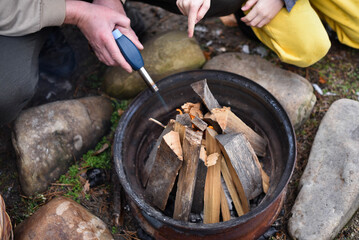 Father and son lighting a fire with a gas gun in the backyard, dressed in winter clothes