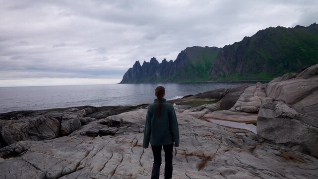 Female tourist walk on rocks with view of Devil's Teeth Okshornan mountain