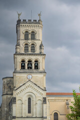 Explore the stunning architecture of the Basilica of Notre-Dame-de-Buglose, located in Saint-Vincent-de-Paul, Landes. The building showcases intricate designs against a moody sky.