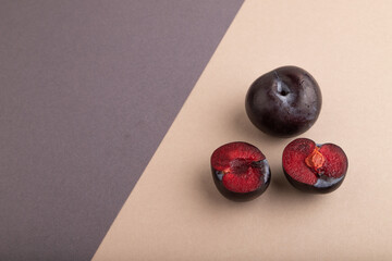 Purple Plum Cut in half beige and gray pastel paper, Side view, copy space
