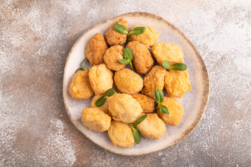 Fried crispy Chicken Nuggets with ketchup, microgreen on brown concrete. top view, close up