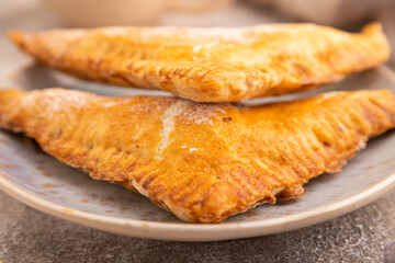 Triangles Pie, Puff Pastry, Samsa with cherry jam on brown concrete, side view, close up, selective focus