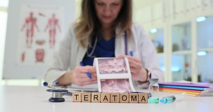 Wooden blocks on medical table spell word Teratoma near syringe. Woman doctor studies tissue scan pictures completing tumor diagnosis report