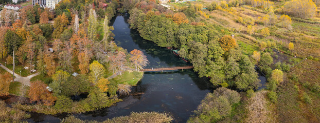 Aerial view of Drilon National Park with a wooden bridge over calm waters and autumn foliage.