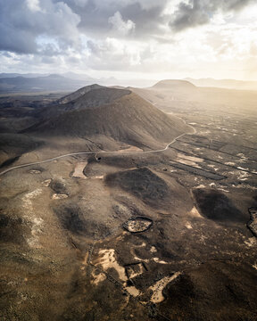Aerial view of volcanic landscapes reveal a stark contrast of textures and tones under a dramatic sky, Fuerteventura, Canary Islands, Spain.