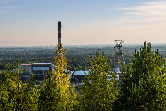 The buildings, chimney and shaft tower of the disused Boże Dary mine illuminated by the setting sun. Kostuchna, Katowice, Silesia, Poland
