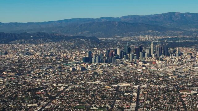 A Delta Airlines plane descends over the Los Angeles skyline for landing, providing a scenic view of the city and aircraft approach from the airplane window.