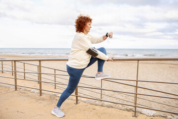 Older woman using wearable technology during her beach workout