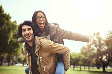 Fototapeta premium Couple, piggy back and fun for portrait in park with care, bonding and adventure in spring on holiday. Interracial love, man and woman with hug, airplane and playful on vacation with game in Toronto