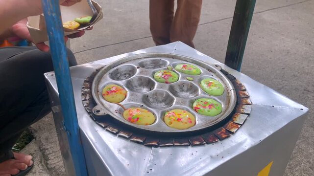 Close up of cooking traditional indonesian street food cake called kue cubit on a special small round mold pan.