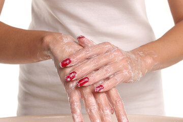 Fototapeta premium Studio shot of woman’s hands covered with soap and foam while washing on white background, hygiene and spa concept.