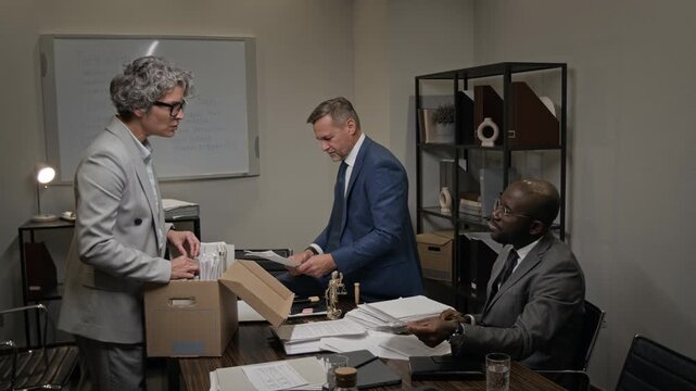 Full shot of diverse team of defense attorneys searching through archive documents while preparing for difficult lawsuit, finding necessary case file then giving each other high fives with joy