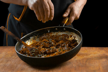 The cook prepares meat with vegetables and onion in a bowl . Oriental cuisine