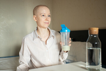 Oncology support concept, cancer patient in casual clothes taking sip of protein supplement from shaker, therapeutic nutrition for weight gain and muscle maintenance after chemo