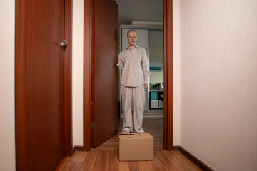 cancer patient at home corridor unboxing brown cardboard package, online marketplace order with comfortable clothing and home essentials, lifestyle of person undergoing chemotherapy.