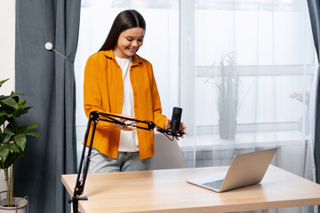 Young woman setting up a studio microphone for recording audio content at home