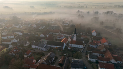 Foggy Bavarian landscape during morning sunrise phase with forest background and small village close which is called P&ouml;rnbach and is located at the region of Pfaffenhofen