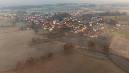 Foggy Bavarian landscape during morning sunrise phase with forest background and small village close which is called P&ouml;rnbach and is located at the region of Pfaffenhofen