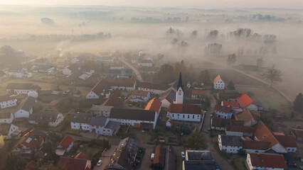 Foggy Bavarian landscape during morning sunrise phase with forest background and small village close which is called P&ouml;rnbach and is located at the region of Pfaffenhofen
