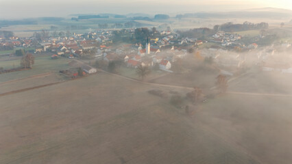 Foggy Bavarian landscape during morning sunrise phase with forest background and small village close which is called P&ouml;rnbach and is located at the region of Pfaffenhofen